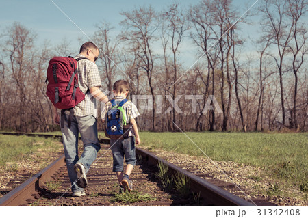 Father and son walking on the railway at the day time. Father and son walking on the railway at the day time. 31342408