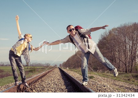 Father and daughter walking on the railway at the day time. Father and daughter walking on the railway at the day time. 31342434