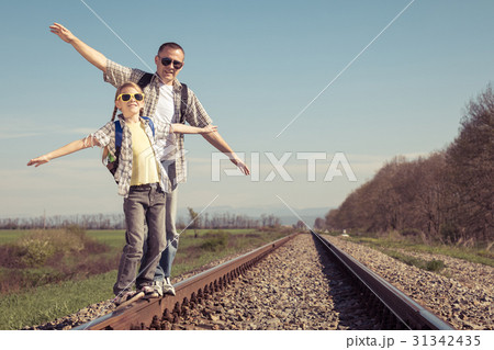 Father and daughter walking on the railway at the day time. Father and daughter walking on the railway at the day time. 31342435