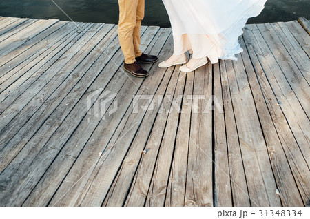A pair of male and female legs stand on a pier A pair of male and female legs stand on a pier 31348334