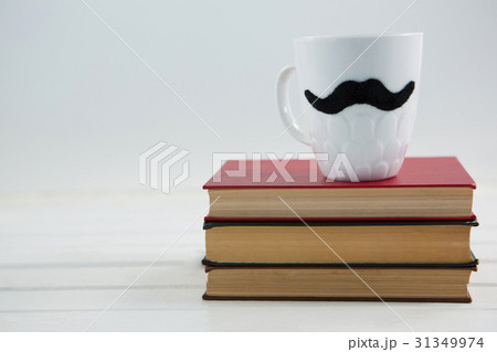Mug with mustache on stack of books 31349974