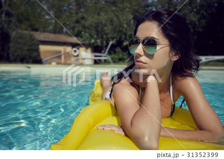 woman in bikini sunbathing on air mattress in the swimming pool 31352399