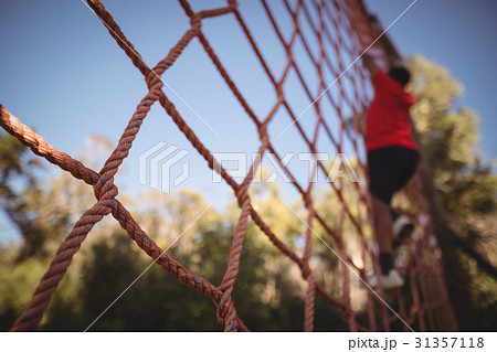 Boy climbing a net during obstacle course Boy climbing a net during obstacle course 31357118