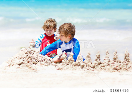 Two kid boys building sand castle on tropical Two kid boys building sand castle on tropical 31363416