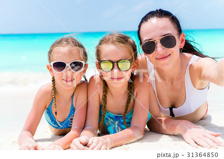 Mother and little girls taking selfie at beach 31364850