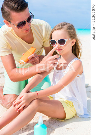 Father applying sun cream to daughter nose 31365070