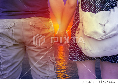 Young couple holding hands on beach at sunset 31375663