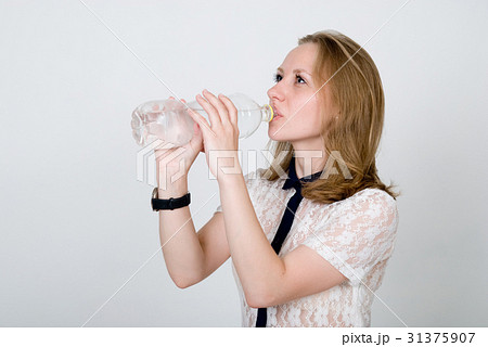 The girl drinks water from a bottle on a white  31375907