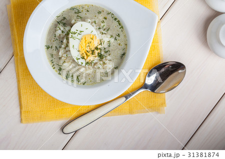 Sorrel soup with egg in white bowl. 31381874