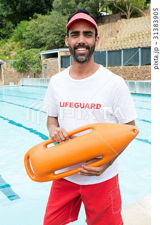 Lifeguard standing with rescue buoy near poolside Lifeguard standing with rescue buoy near poolside 31383905