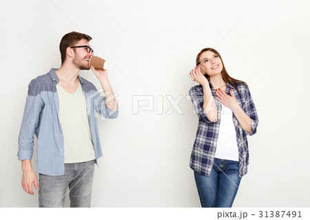 Young casual couple talking through tin can phone 31387491