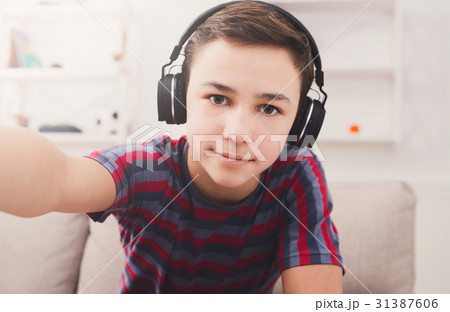 Boy in headphones taking selfie at home Boy in headphones taking selfie at home 31387606
