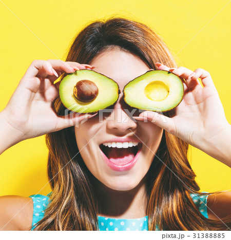 Happy young woman holding avocado halves Happy young woman holding avocado halves 31388885