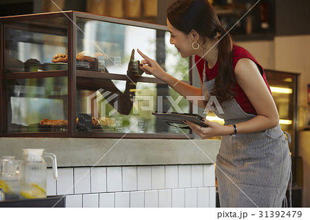 a woman is looking and pointing cakes in a shop window. a woman is looking and pointing cakes in a shop window. 31392479