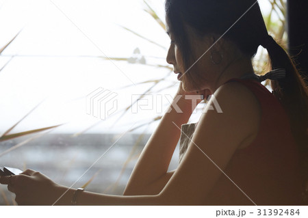a portrait of a woman with tablet sitting nearby window. a portrait of a woman with tablet sitting nearby window. 31392484