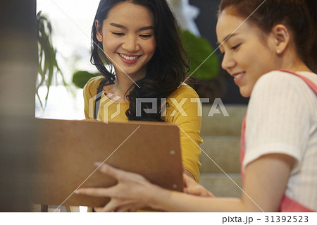two women are smiling and looking something. two women are smiling and looking something. 31392523