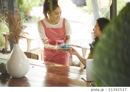 A waitress is giving a cup of coffee to a customer. A waitress is giving a cup of coffee to a customer. 31392537