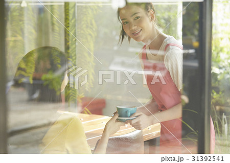 a waitress is serving drink for customer when she looks outside. a waitress is serving drink for customer when she looks outside. 31392541