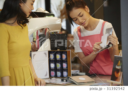 a barista is holding a menu to recommend beverages for a woman. 31392542