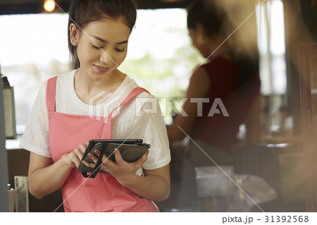 Beautiful waitress is using a digital tablet and smiling. 31392568