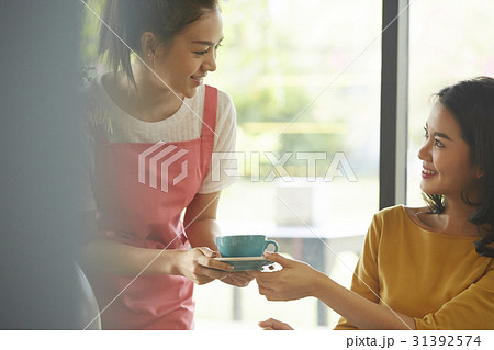 The waitress is serving coffee and smiling at a customer in the cafe. The waitress is serving coffee and smiling at a customer in the cafe. 31392574