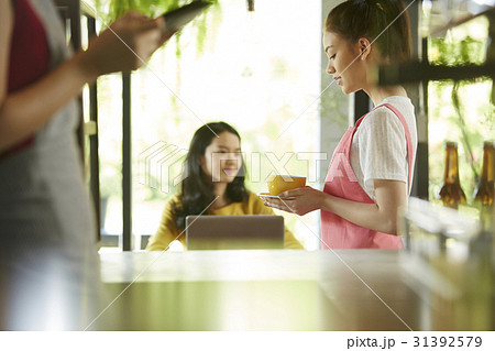 A waitress is holding a cup and customer is sitting in the café. A waitress is holding a cup and customer is sitting in the café. 31392579