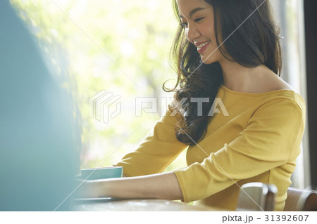Young woman is smiling and sitting in the cafeteria. 31392607
