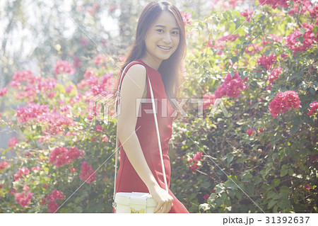 A photo of a happy woman enjoying flowers outdoor. 31392637