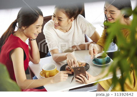 Female colleagues are discussing something funny in smartphone. Female colleagues are discussing something funny in smartphone. 31392642