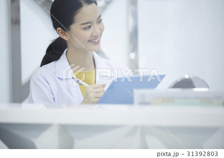 A beautiful doctor is writing down on a clipboard and smiling. 31392803