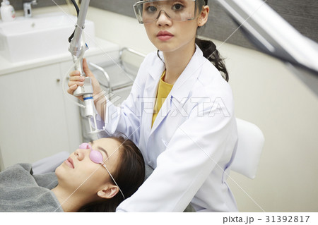 A female doctor with safety grasses is using laser equipment and looking. 31392817