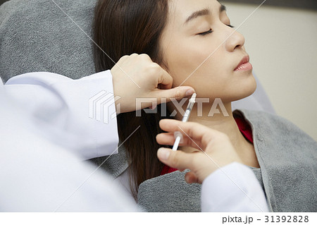 Someone is Injecting botox into a woman's face. 31392828