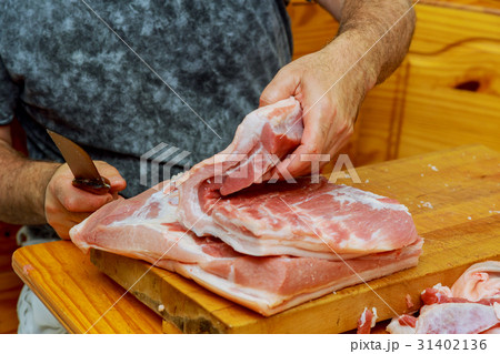 Midsection of butcher cutting meat with cleaver  31402136