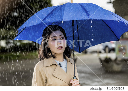 雨の降る街頭をリポートする女子アナ 31402503