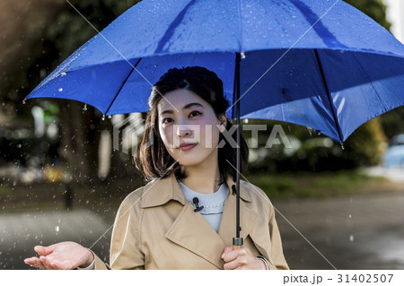 雨の降る街頭をリポートする女子アナ 雨の降る街頭をリポートする女子アナ 31402507