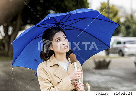 雨の降る街頭をリポートする女子アナ 31402521