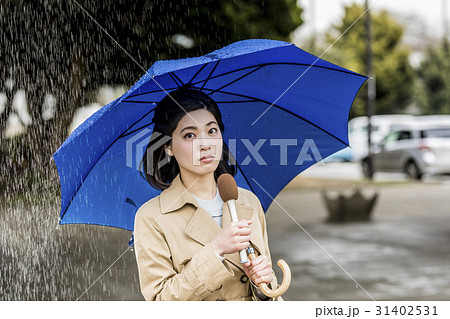 雨の降る街頭をリポートする女子アナ 31402531