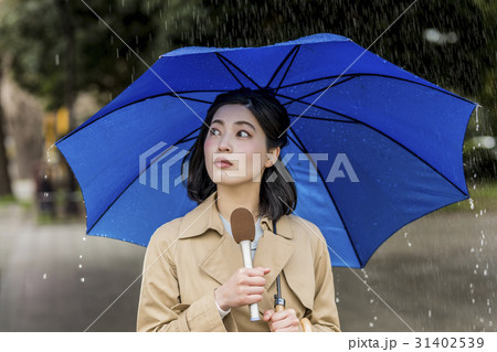 雨の降る街頭をリポートする女子アナ 31402539