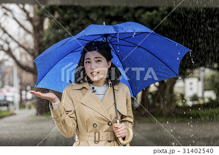 雨の降る街頭をリポートする女子アナ 31402540