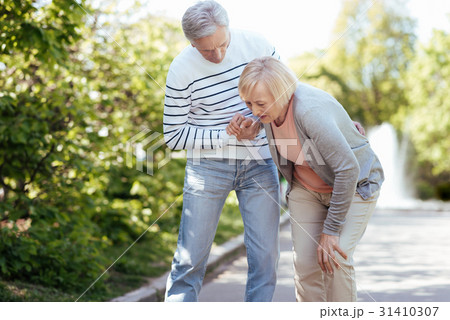 Caring pensioner helping senior wife outdoors 31410307