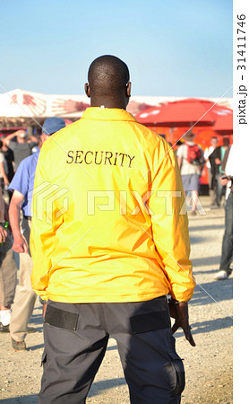 Black security guard wearing yellow jacket 31411746