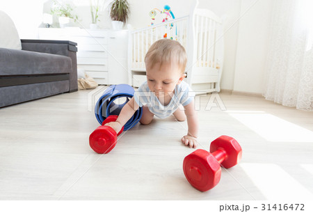 Baby exercising with dumbbells on floor at home 31416472