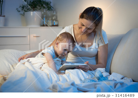Baby boy sitting on bed with mother 31416489