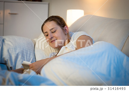 Woman reading on digital tablet at bed before 31416493