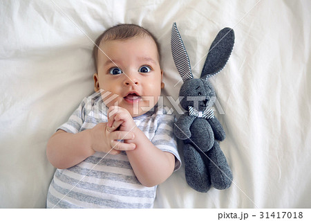 the child lies on his back on a big white bed 31417018