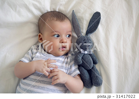 the child lies on his back on a big white bed 31417022