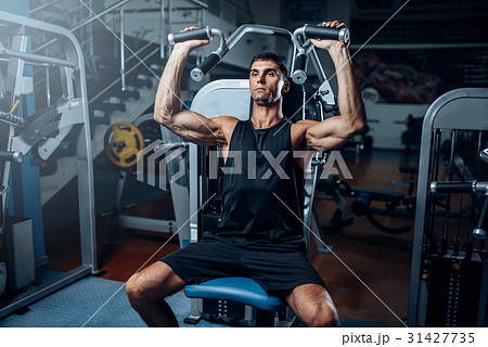 Tanned man training on exercise machine 31427735