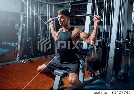 Tanned athlete workout on exercise machine in gym 31427740