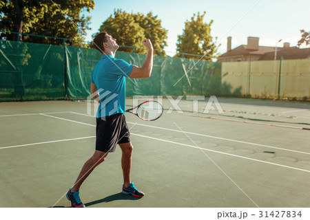 Man with tennis racket on outdoor court 31427834