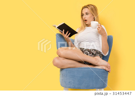 Young woman sitting at blue armchair Young woman sitting at blue armchair 31453447